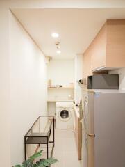 Compact laundry room with washing machine, refrigerator, and storage shelves