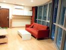 Modern living room with large window, red couch, and wooden flooring