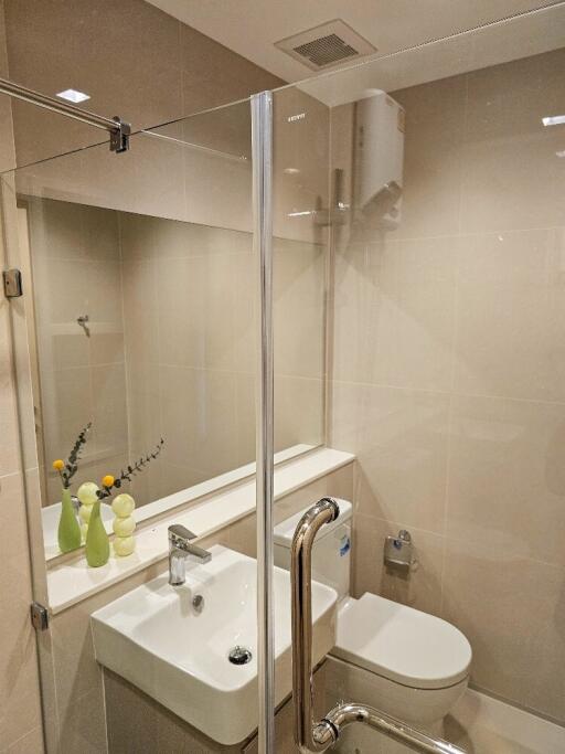 Modern bathroom with glass-enclosed shower area, sink, and toilet