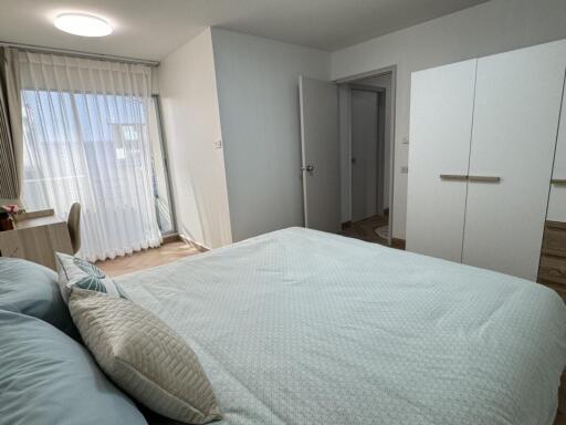 Modern bedroom with bed, wardrobe, desk, and window with curtains