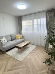 Bright living room with a cozy sofa, coffee table, and large window with curtains