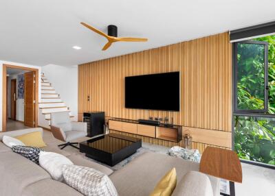 Modern living room with wooden panel wall, large TV, and natural light