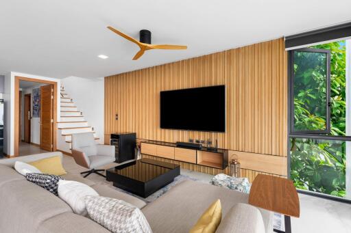 Modern living room with wooden panel wall, large TV, and natural light