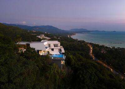 Aerial view of a modern house on a hill overlooking the ocean at dusk