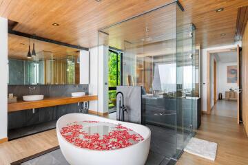 Modern bathroom with glass shower enclosure and bathtub with rose petals