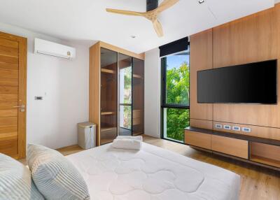 Modern bedroom with wooden accents, large windows, and mounted TV