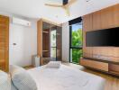 Modern bedroom with wooden accents, large windows, and mounted TV