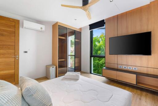 Modern bedroom with wooden accents, large windows, and mounted TV