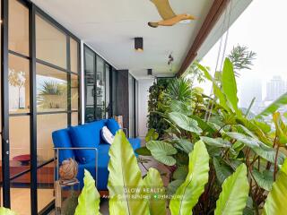 Modern balcony with blue sofa and lush green plants