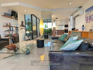 Modern living room with glass coffee table and black leather sofa