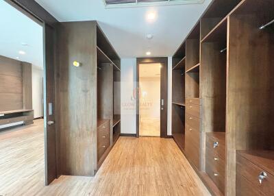 large walk-in closet with wooden shelves and drawers