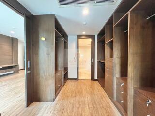 large walk-in closet with wooden shelves and drawers