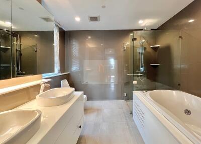 Modern bathroom with dual sinks, a bathtub, and a glass-enclosed shower