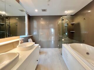 Modern bathroom with dual sinks, a bathtub, and a glass-enclosed shower