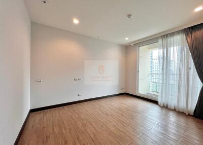 Spacious bedroom with wooden flooring and large window