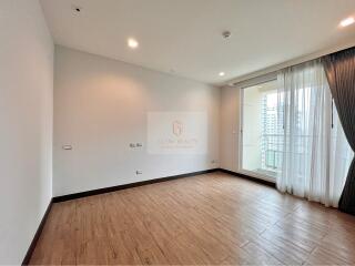 Spacious bedroom with wooden flooring and large window