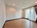 Spacious bedroom with wooden flooring and large window