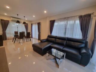 Modern living room with black leather sofa and dining area