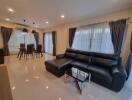 Modern living room with black leather sofa and dining area