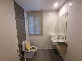 Modern bathroom with toilet, sink, and large mirror.