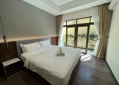 Bedroom with large bed, bedside table, floor-to-ceiling windows and curtains