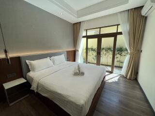 Bedroom with large bed, bedside table, floor-to-ceiling windows and curtains