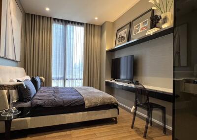 Modern bedroom with bed, bedside table, wall art, and TV