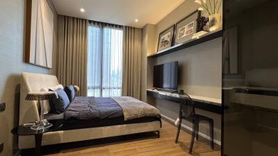 Modern bedroom with bed, bedside table, wall art, and TV