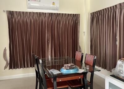 Dining room with a glass-top table, six chairs, brown curtains, and air conditioning