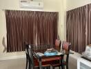 Dining room with a glass-top table, six chairs, brown curtains, and air conditioning