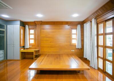 Spacious wooden bedroom with high ceiling and large windows