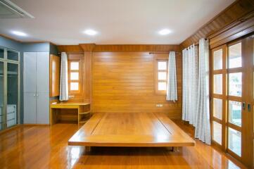 Spacious wooden bedroom with high ceiling and large windows