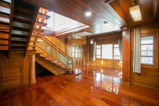 Spacious wooden living area with staircase and large windows