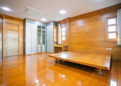 Spacious wooden-themed bedroom with built-in wardrobes and large platform bed