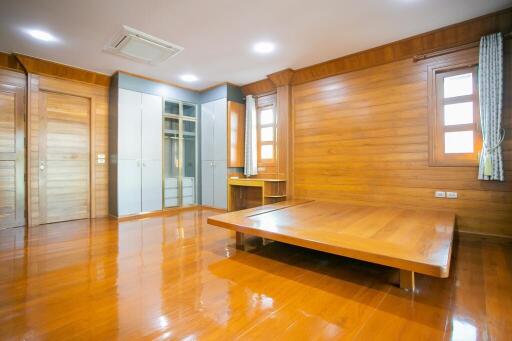 Spacious wooden-themed bedroom with built-in wardrobes and large platform bed