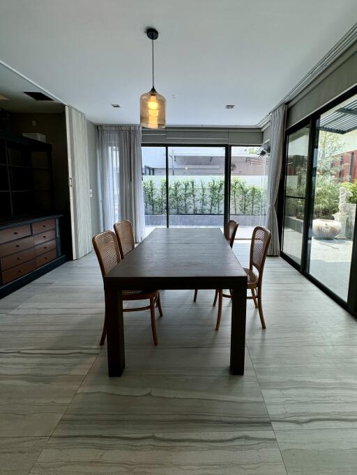 Modern dining room with wooden table and chairs, large windows, and garden view