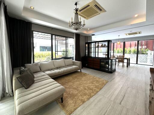 Spacious and modern living room with large windows, sectional sofa, and dining area
