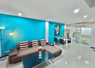 Modern living room with turquoise accent wall, sectional sofa, and dining area