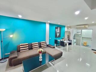 Modern living room with turquoise accent wall, sectional sofa, and dining area