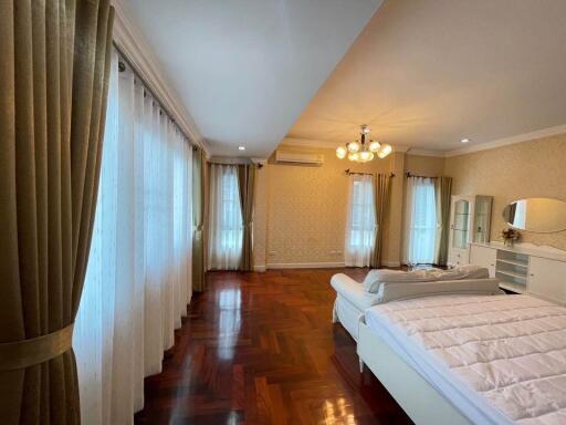 Spacious and well-lit bedroom with wooden flooring and elegant decor