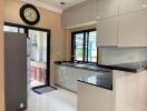 Modern kitchen with beige walls, black countertops, and large windows