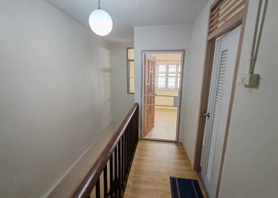 hallway with wooden railing and door leading to another room