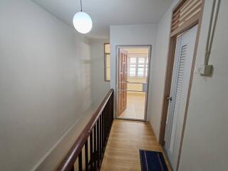 hallway with wooden railing and door leading to another room