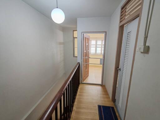 hallway with wooden railing and door leading to another room