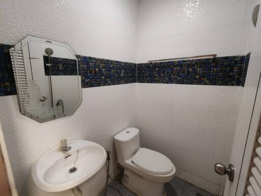 Bathroom with sink, toilet, mirror, and tiled walls