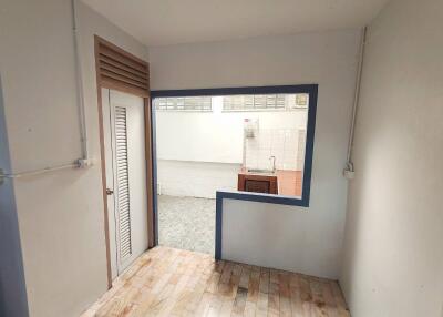 Small partially enclosed kitchen with a window opening to an adjacent room.