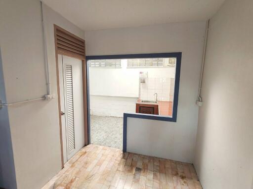 Small partially enclosed kitchen with a window opening to an adjacent room.