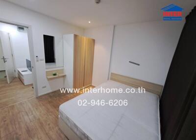 A well-furnished bedroom with a wooden floor, bed, wardrobe, and dressing table.