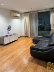 Living room with black leather couch and large window