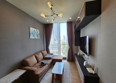 Modern living room with brown couch, coffee table, TV, and large windows